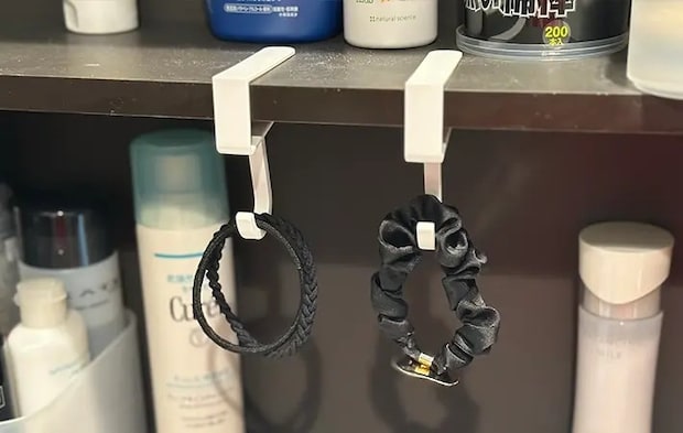 洗面台の棚に引っかけた『吊り戸棚用フック』にヘアゴムと髪飾りを吊るしている（撮影：grapeライフハック編集部）