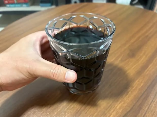 手に持ったアイスコーヒーのグラス（撮影：grapeフード編集部）