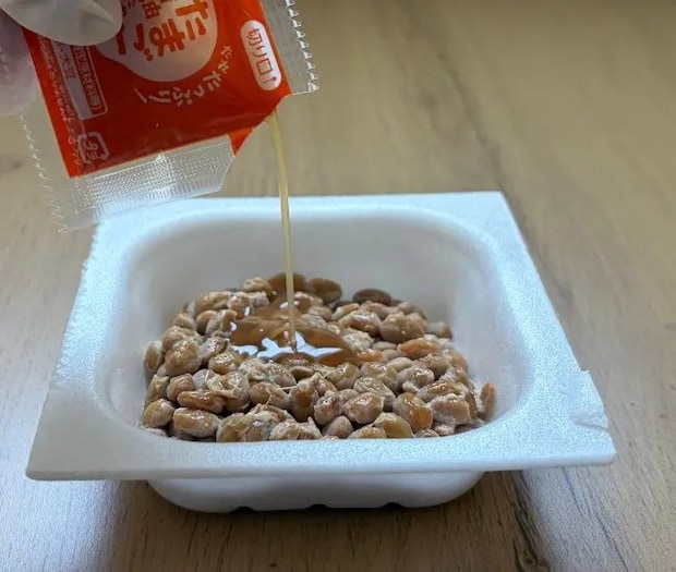 混ぜる前の納豆にタレを入れる写真（撮影：grapeフード編集部）