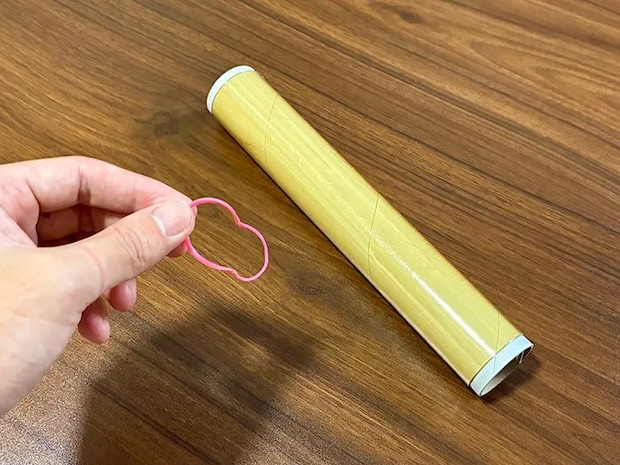 手で持った輪ゴムと、机に置かれたラップ（撮影：grapeライフハック編集部）