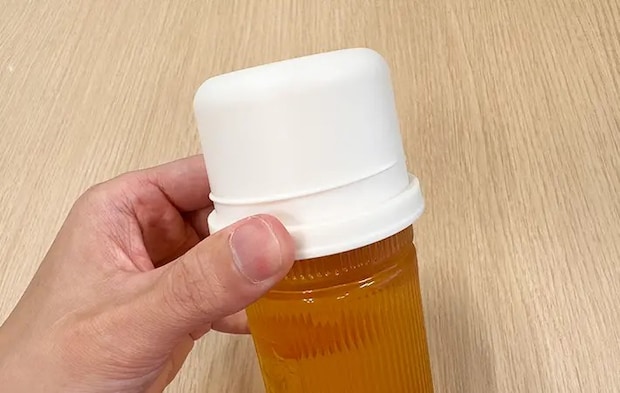 スリコのハンドル付きペットボトル用コップをペットボトル飲料につけている写真（撮影：grape編集部）