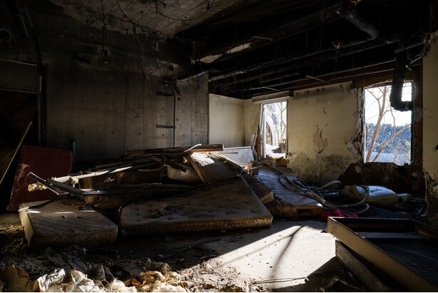 剥がれ落ちた壁紙や家具が放置されている