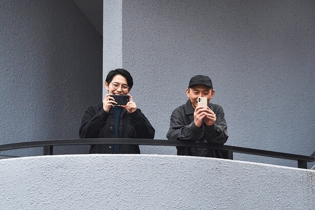 遠くの塀の上から撮影を試みるカメラマンの姿を面白がってくれた2人