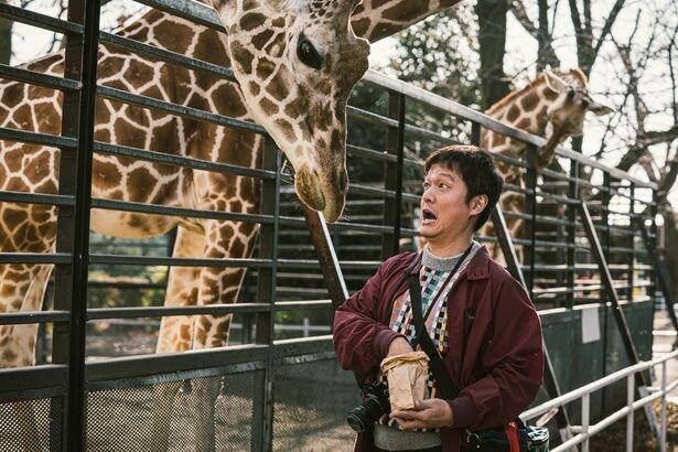 【写真を見る】キリンに餌をｱあげる丸山隆平の無邪気な一幕を切り取ったオフショット