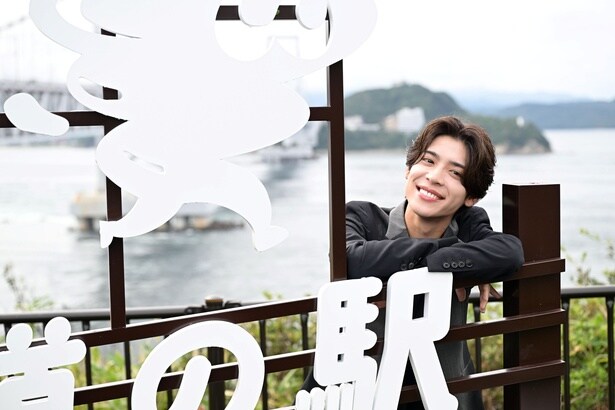 うず助のモチーフである鳴門海峡、大鳴門橋、淡路島の海をバックにニコニコの松島