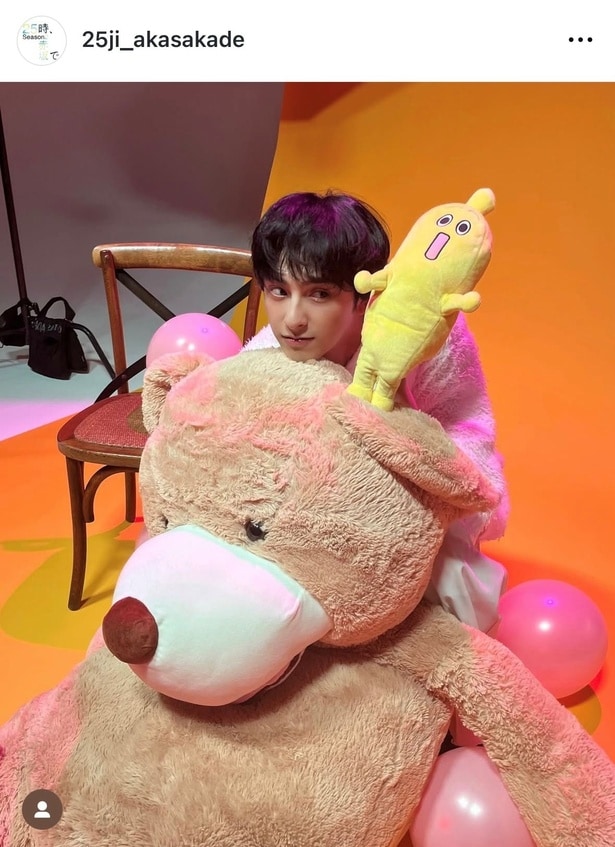 カメラから目線を外した新原泰佑と特大テディベア