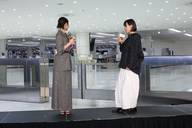 手荷物受取所を見渡しながら空港でのイベント開催の心境を語る有村架純と天野千尋監督
