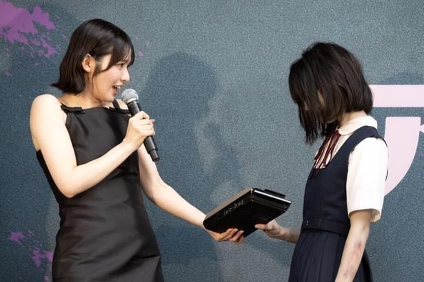 "だぁれかさん”にカセットテープレコーダーを渡す鎮西寿々歌
