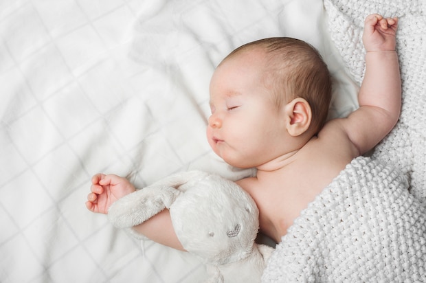 Sleeping newborn boy 2 months old with toy on white background close up and copy space 99813132