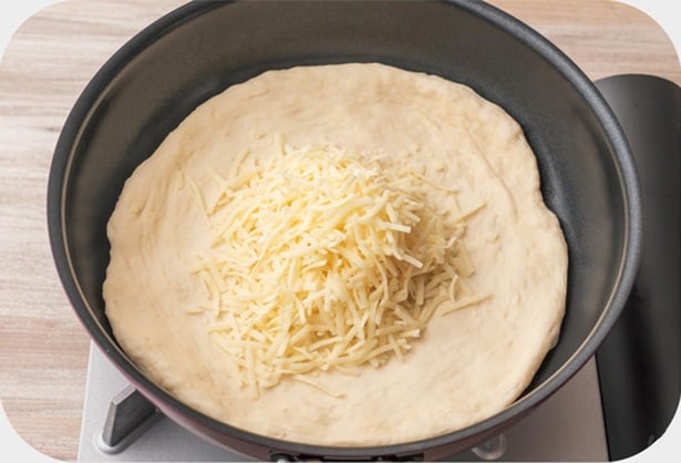 フライパンに生地を入れてのばし、ピザ用チーズをのせる