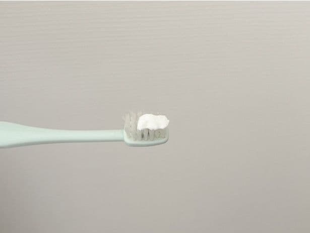 歯ブラシに歯磨き粉を適量出す(▶次へ)