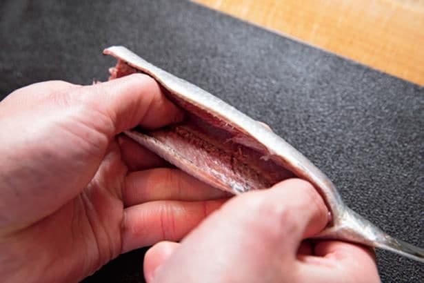 いわしのさばき方2　腹側から中骨の上にまん中から親指を入れ、両脇へとゆっくり開く