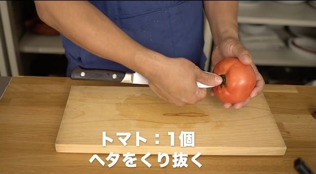 トマトのヘタのところに、包丁を少し斜めに向けて刺す