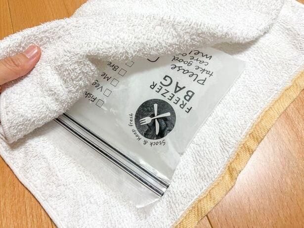 凍ったジップ付き保存袋をタオルで包む（▶次へ） 