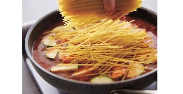 スパゲッティを半分に折ってからソースを煮立てたフライパンに加えて混ぜる
