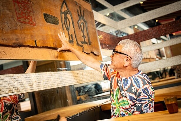 1985年の創業当時にかかっていた一枚板の看板の前で