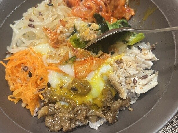 炭火焼肉や蒸し鶏、野菜やキムチとたくさんの具材をよく混ぜて