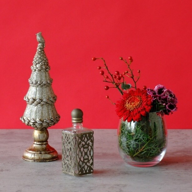 クリスマスツリーオブジェと並ぶ華やかなミニアレンジ。グリーンやベリーが冬のテーブルを彩り、ホリデー感あふれるインテリアに仕上がる
