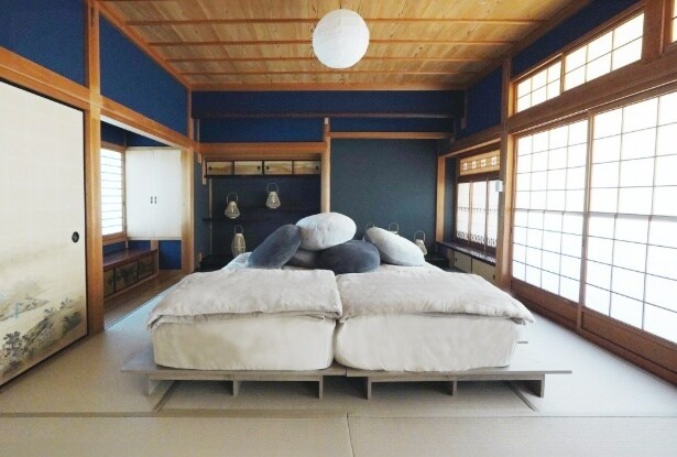 深い藍色の壁と木の天井が醸す静けさの中に、柔らかな寝具がそろった和室空間が広がる