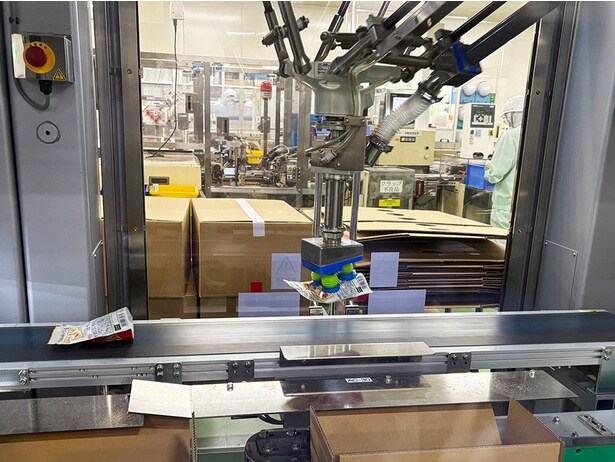 青と緑の吸盤のようなもので流れてくるパウチをキャッチ、手前の段ボール箱に入れていく