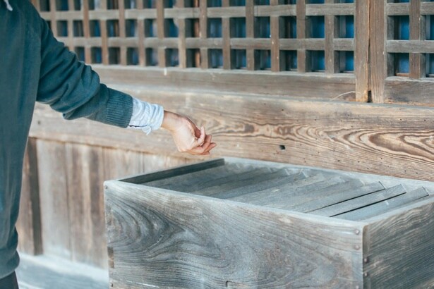 お賽銭は賽銭箱にそっと置くようにして入れる