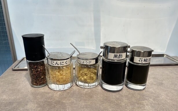 刻みニンニク、黒酢、花椒などの卓上調味料で“味変”できる