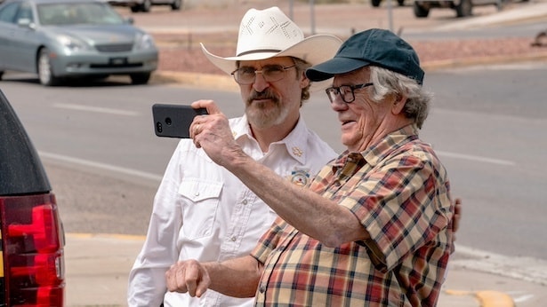 自分と同様にマスクをしない老人とセルフィーを撮るジョー(ホアキン・フェニックス)