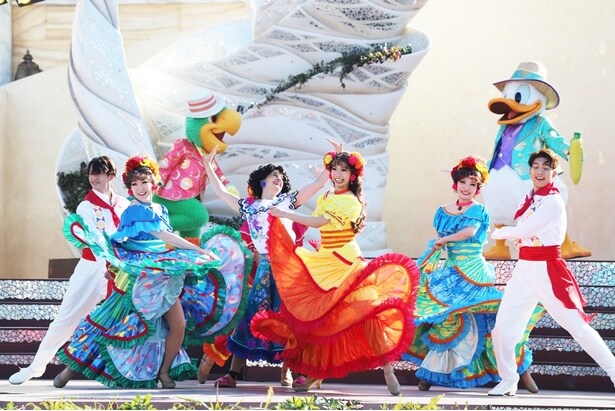 カラフルな衣装を身にまとったダンサーに囲まれ、元気いっぱいに踊るミラベル