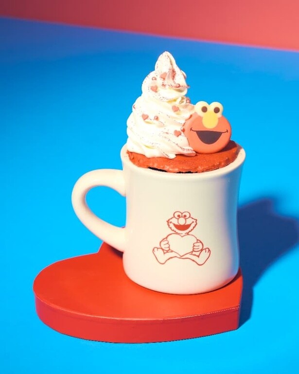 「エルモ ホットチョコレート」。ダイナーマグの上にはチョコでコーティングしたパイをのせ、さらにその上にたっぷりのホイップとエルモの顔チョコをトッピング！