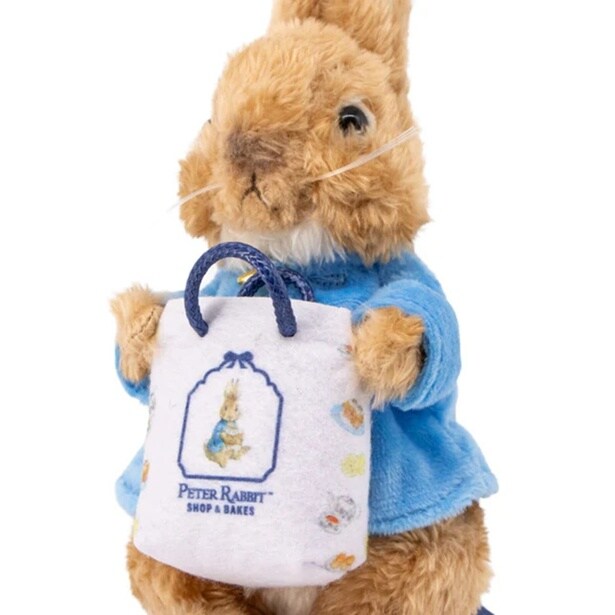 抱えたショップバッグには「PETER RABBIT SHOP & BAKES」のロゴ入り。