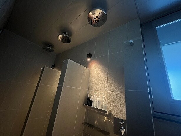 温かいお風呂の前に天井固定タイプのシャワーブースが3つ並ぶ