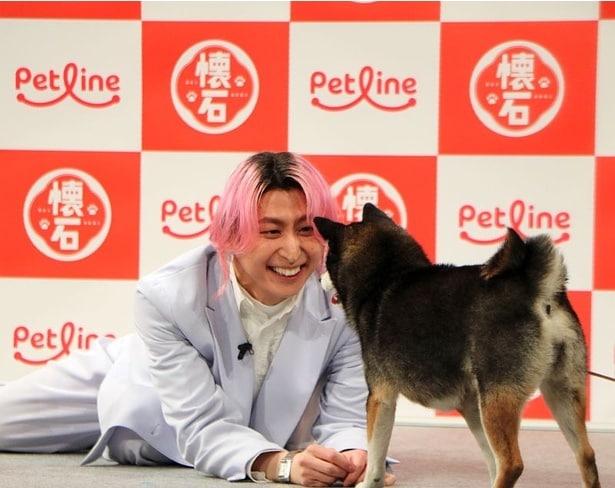 【写真】床の上に寝転がってワンちゃんと戯れる佐久間さん
