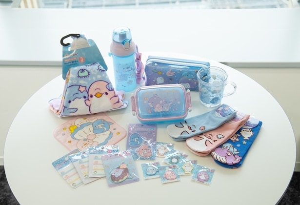 奥列左から右に向かって、「ループ付きタオル」(550円)、「抗菌直飲プラワンタッチボトル」(1870円)、「BOXペンポーチ Night Sea」(2310円)、「抗菌ふわっとフタタイトランチボックス」(1485円)、「ウォーターカップ」(858円)、前列奥列左から右に向かって、「プチタオル(5枚セット)」(539円)、「ネームシール」(各352円)、「シールワッペン(アオイルカ＆めんだこ)」(715円)、「マットヘアクリップ」(990円)、「シールワッペン(小)」(各495円)、「ソックス」(各550円)