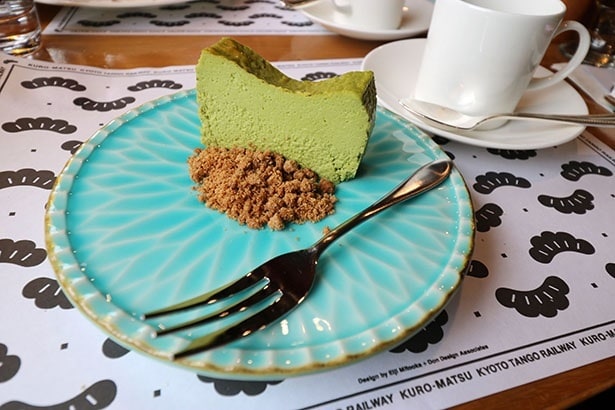 「天橋立の緑景　抹茶チーズケーキ」。海を思わせる青い皿に、松並木をイメージした自家製の抹茶チーズケーキ。クッキーを砕いたクランブルで砂浜を表現している