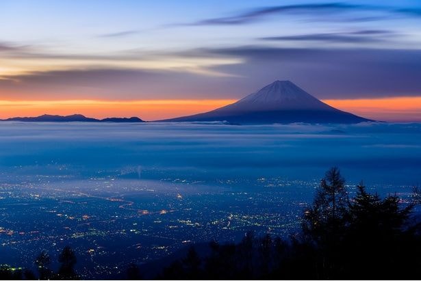 雲海とともに浮かび上がる富士山と街の灯りが、非日常のひとときを演出