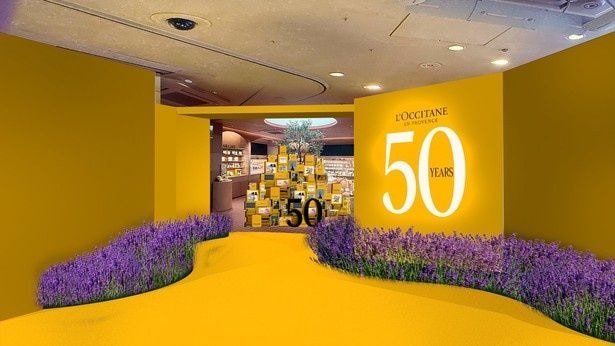 ロクシタンイエローに彩られたエントランスとラベンダーの壁面装飾が来場者を迎える1階フロア