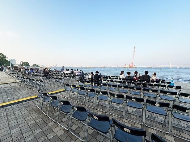 臨港パークのパイプ椅子席。海上から伸びるクレーンに仕掛け花火が点火する