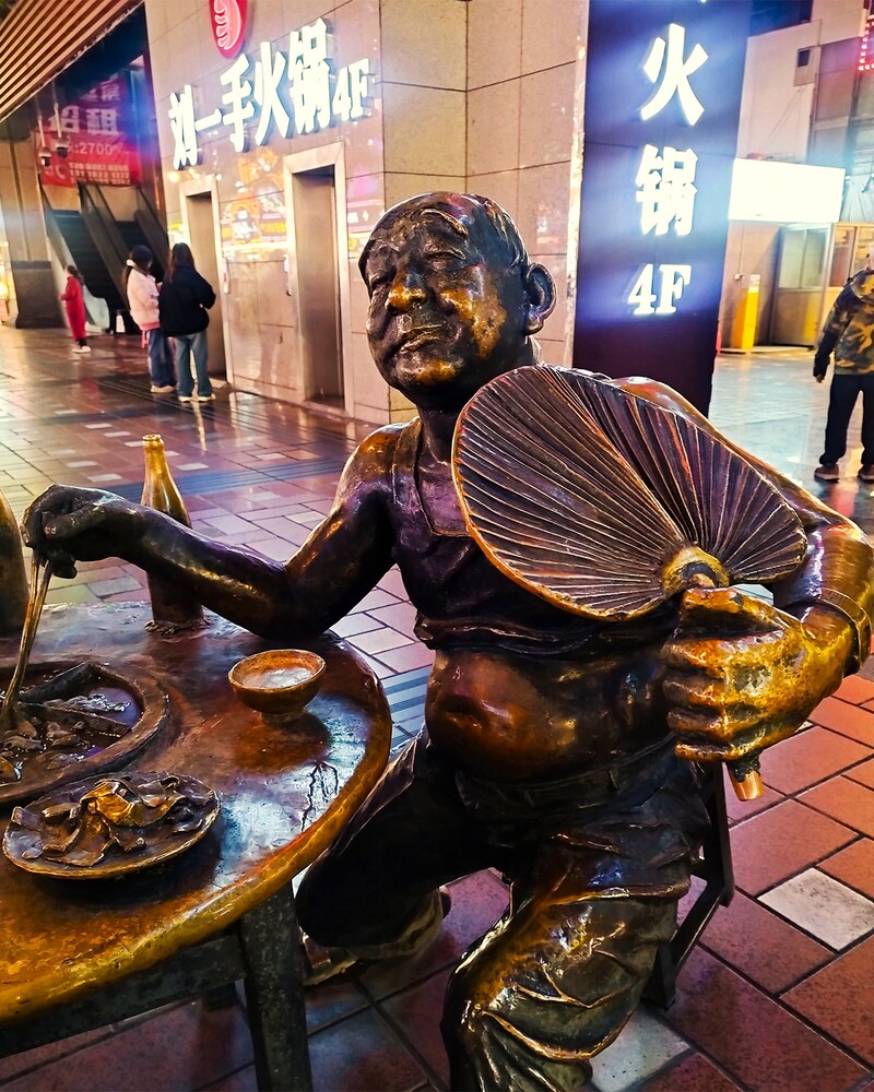 重慶中心地の路上に陣取る火鍋おじさん像。腹を出し、うちわで仰ぎながら火鍋を食す、自然体すぎる楽しい食事風景がほほえましい