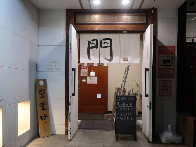  福井市の『らーめん門（かど）』の入口。福井口駅（えちぜん鉄道）から徒歩10分程度。国道8号線から1本中に入った通り沿いにある。白地に黒文字で大きく「門」と書かれた暖簾が目印