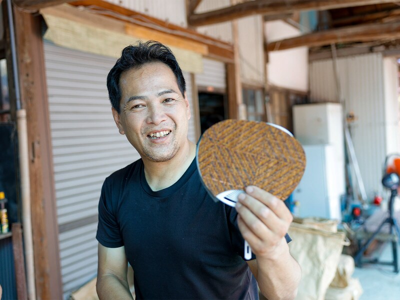 紙布製のうちわを手にする5代目社長の津島久人さん。所要時間30分前後でうちわづくりを体験可能。余った紙布でしおりもつくれる