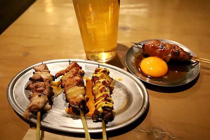 手前：純けいもも串 各180円、奥：純けい生つくね月見 250円、ビール　490円