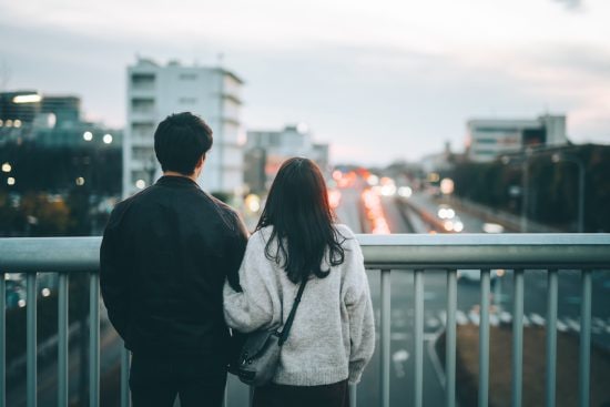 歩道橋から夜景を眺めるカップル