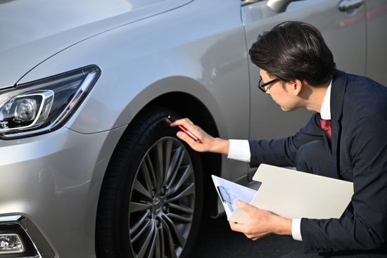 車の傷を確認するビジネスマン
