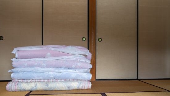 畳まれた敷き布団と和室