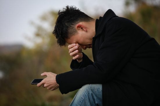 スマートフォンを見て泣く男性