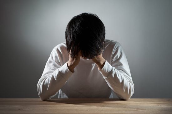 暗い部屋で落ち込むアジア人男性