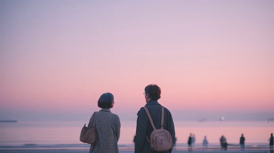 夕暮れの海べで佇む中高年のカップル