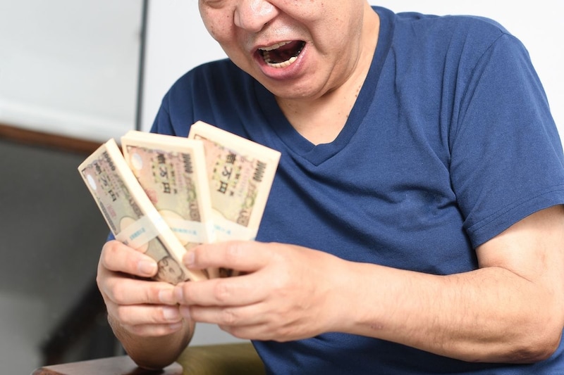 札束を持つ笑顔の男性