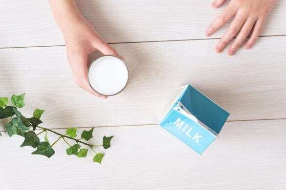 グラスに入った牛乳を飲む人と牛乳パック