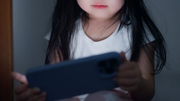 夜に暗い部屋でスマホを見る子ども